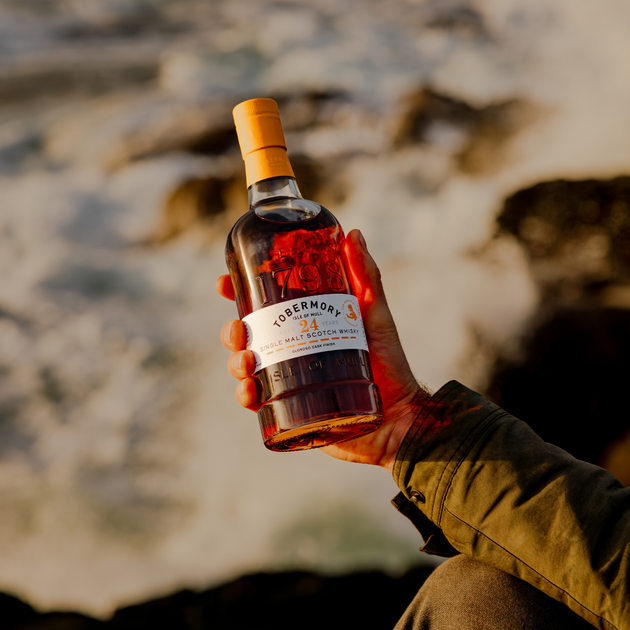 Man Holding Hebridean Series 24 Year Old Bottle with Coastal Backdrop